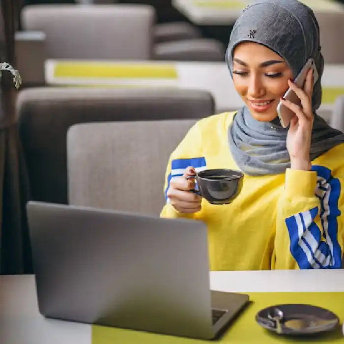 Woman enjoying coffee while speaking on the phone during an online banking consultation.